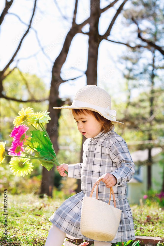 Toddler girl holidng daisy flowers outside in spring