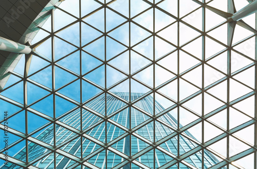 Looking up at a skyscraper and sky above through grid glass awning