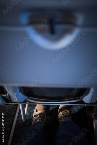Passanger's legs squeezed between aircraft seats. Not too much space for legs.