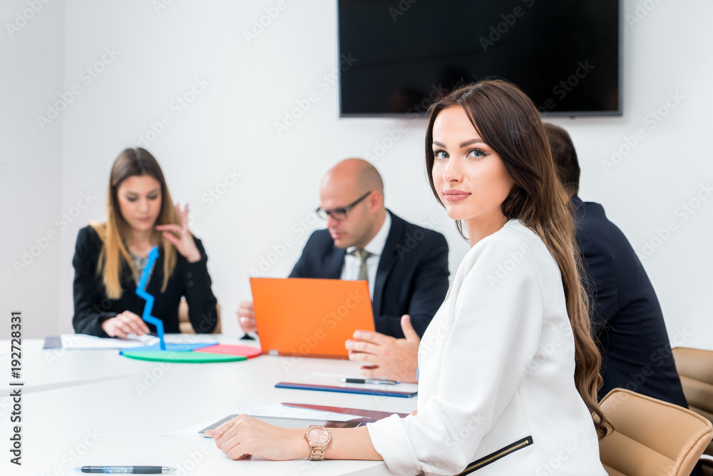 Beautiful business woman is looking at camera and smiling while working in office Beautiful business woman is looking at camera and smiling while working in office