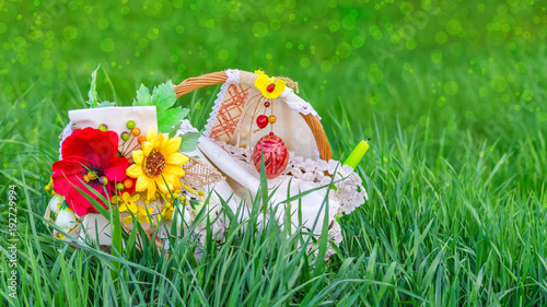 Easter basket in green grass, on a blurred background of meadow with bokeh effect