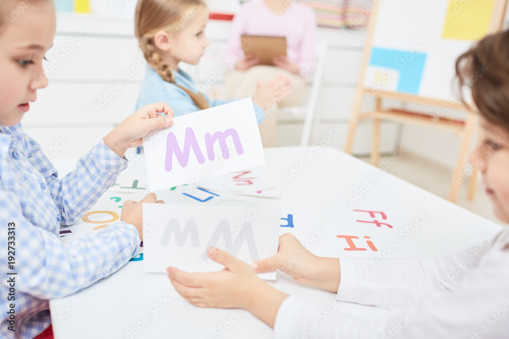 Two kids choosing paper cards with english letters during lesson in kindergarten or elementary school Two kids choosing paper cards with english letters during lesson in kindergarten or elementary school
