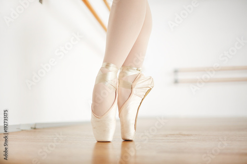 Feet of ballerina in beige pointes standing on toes during repetition