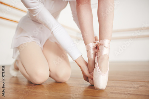Ballet teacher helping her learner to keep standing on toes during training