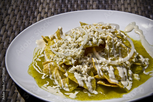 Green Chilaquiles with fresh crumbled cheese and sour cream, hard light close-up. photo