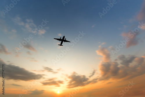 Silhouette of turboprop airplane flying in orange sky at sunset, wide angle, focus on plane, blurred clouds, copy space/ View of a flying airplane from below/ Vacation, aviation, trip concept © DimaBerlin