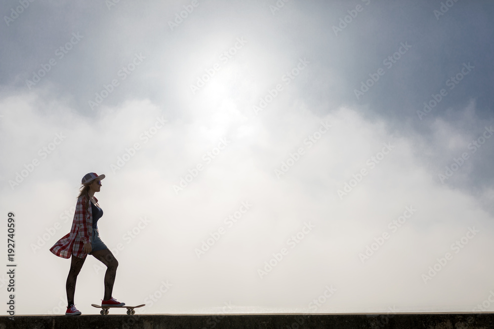 Silhouette of cute girl riding a skateboard near the beach