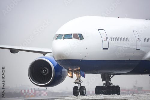 Bad weather, aviation, transportation, travel concept/ Close up of wide-body airplane taxing on runway after landing, low-cloud conditions, poor visibility, foggy weather in cold season, horizontal