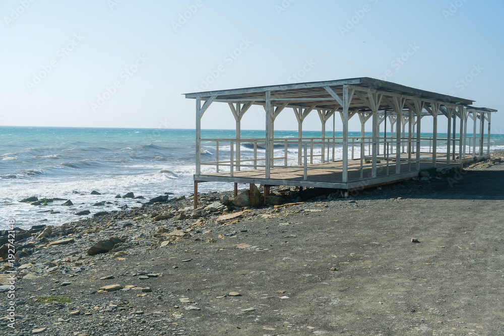 The old white terrace at the seaside in winter. Pebble beach.