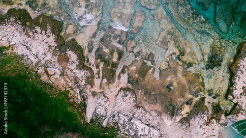 Aerial view of waves break on rocky beach. Sea waves on the beautiful colorful rocky beach. Aerial view drone 4k shot. Zoom in