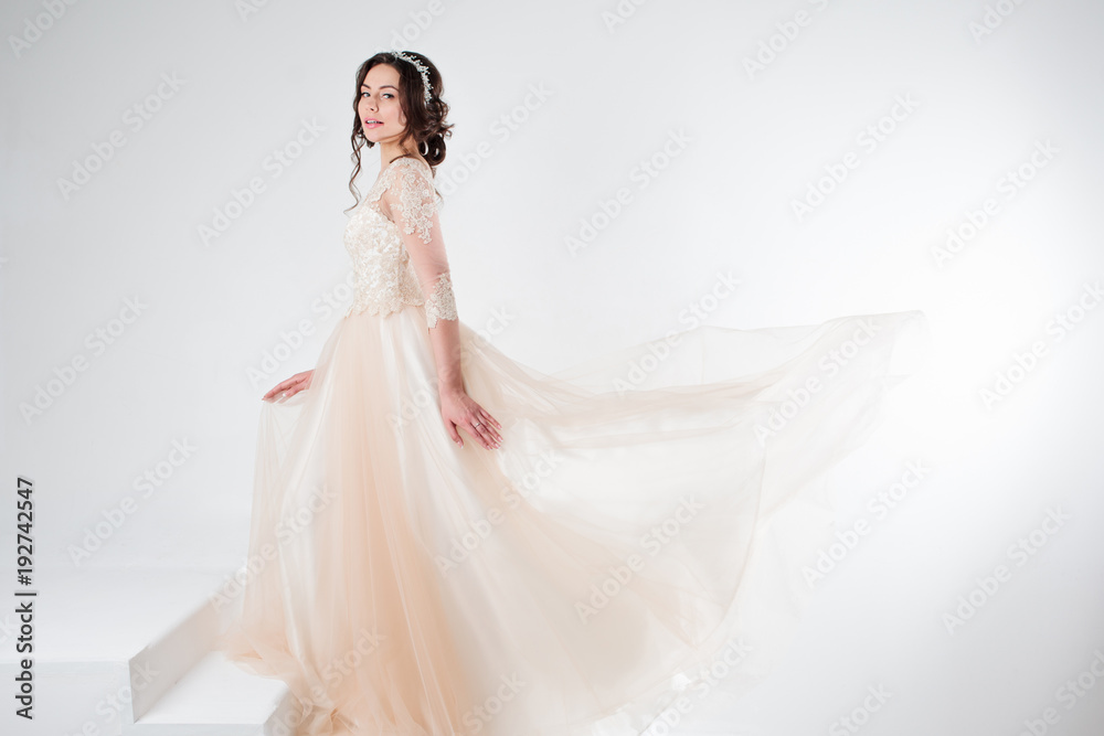 Fototapeta premium Portrait of a beautiful girl in a wedding dress. Bride in a luxurious dress standing on the stairs, climb up