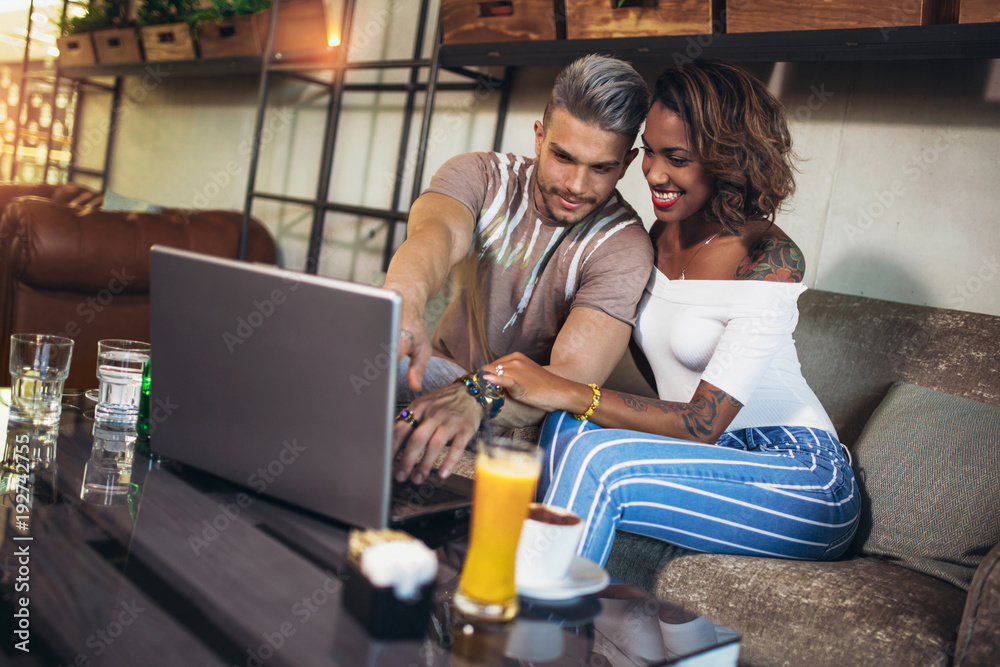 Young interracial lovers spending time in cafe watching media together on laptop Young interracial lovers spending time in cafe watching media together on laptop
