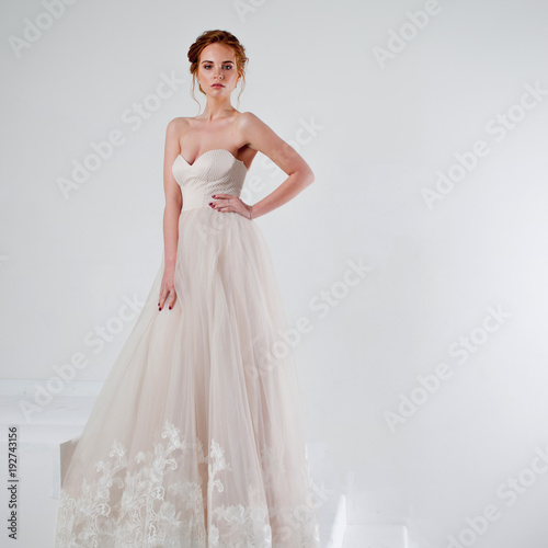 Portrait of a beautiful girl in a wedding dress. Bride in luxurious dress on a white background