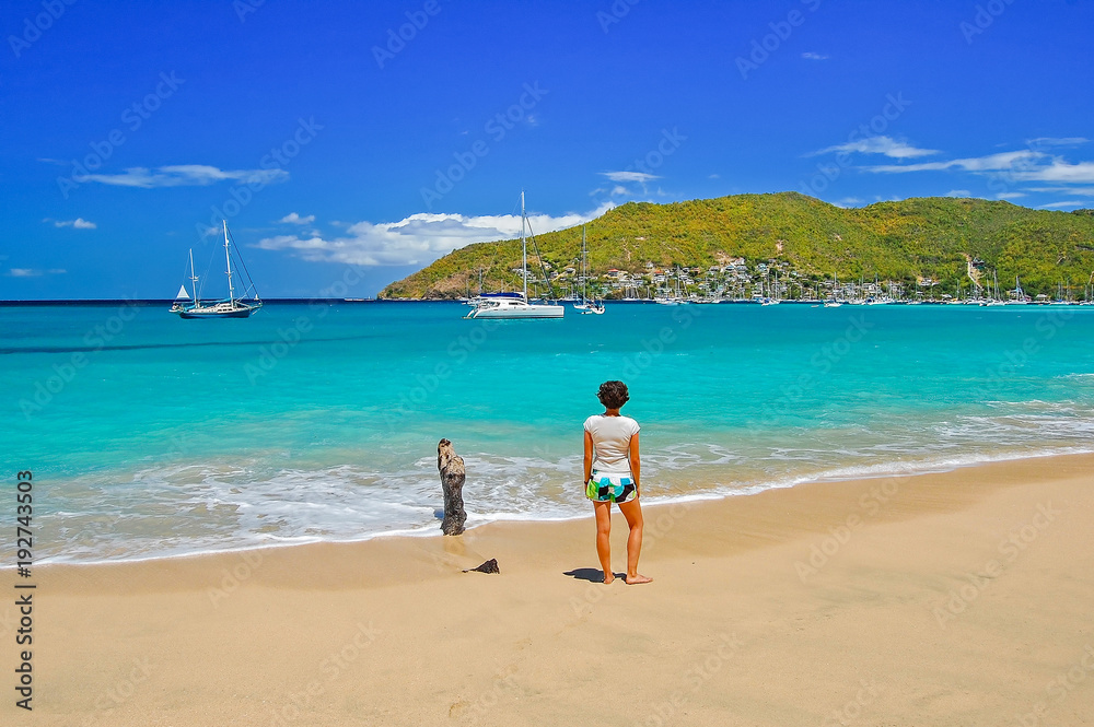 Woman on beautiful beach on Bequia Island with boats in the distance, Caribbean Sea region of Lesser Antilles Woman on beautiful beach on Bequia Island with boats in the distance, Caribbean Sea region of Lesser Antilles