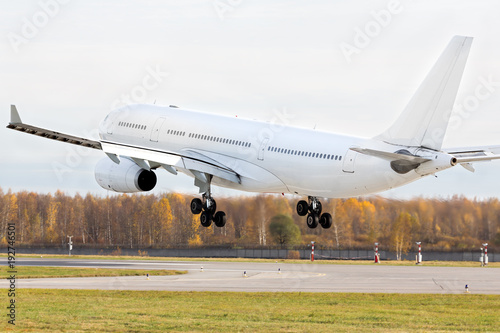Close up of wide-body modern passenger airplane almost landed at the runway/ Low over the runway, copy space/ Very hot air behind the aircraft engine/ Vacation, aviation, travel, trip - concept/ 