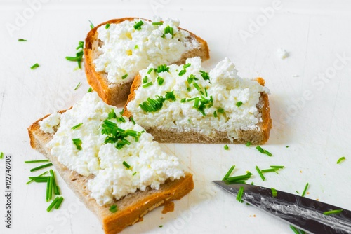 3 slices of bread with curd cheese and chive on white.