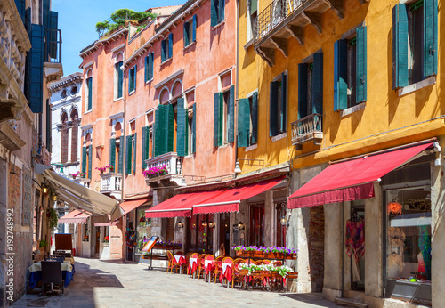 Colorful street with tables of cafe at a sunny morning, Venice, Italy.
