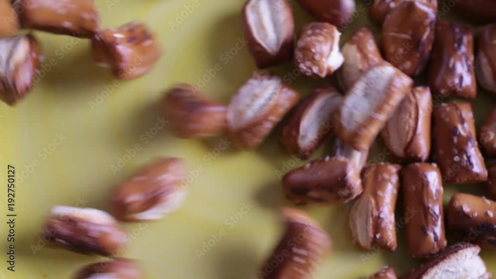 Close view of a several bite size sourdough pretzels being poured onto a yellow plate. Close view of a several bite size sourdough pretzels being poured onto a yellow plate.