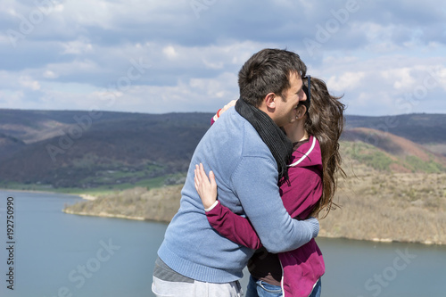 Happy Young Couple Hugging on a Lake Background