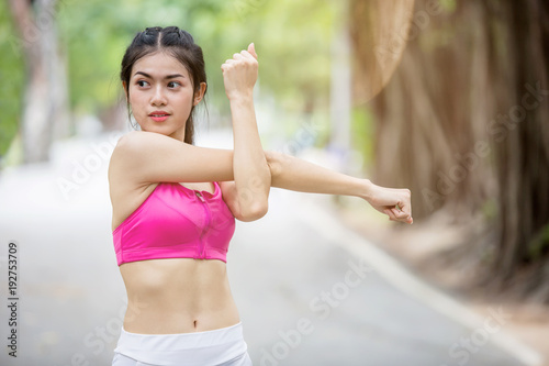 Young Asian woman stretching body after workout in the park