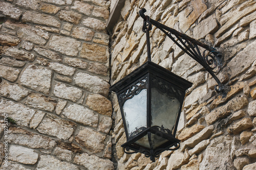 The iron lantern hangs on the old stone wall.