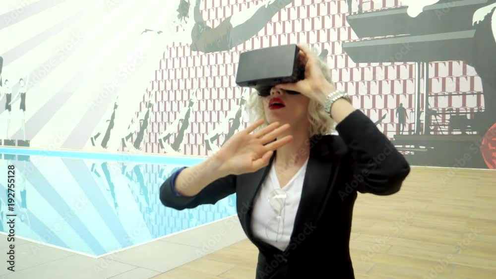 a young blonde with bright lipstick on her lips participates in the passage of a virtual game on the phone, a woman dressed virtual reality glasses in a special room