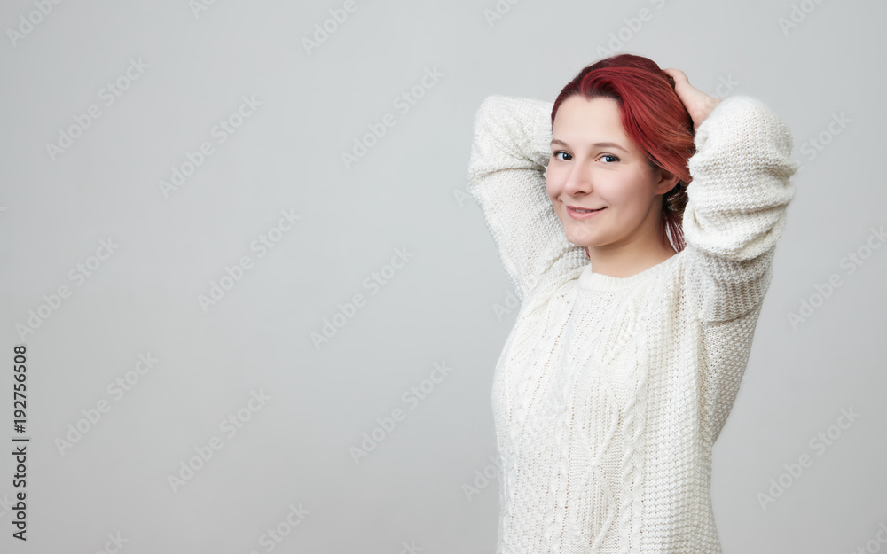Happy beautiful redhead girl in white sweater, smiling touching correcting her red hair over white background with copy space. Happy beautiful redhead girl in white sweater, smiling touching correcting her red hair over white background with copy space.