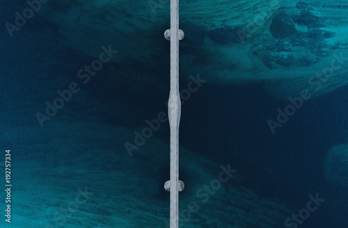 Aerial shot of a bridge over sea strait. Visible depth with blue and green colours near Tromso. Sommaroy, Norway