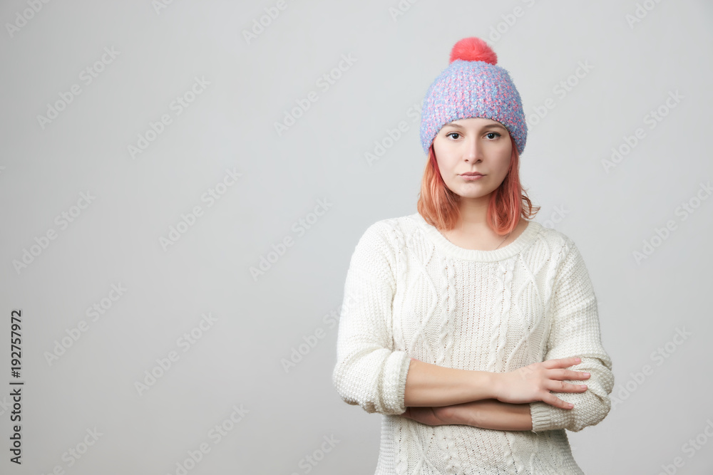 Portrait of offended unhappy beautiful woman in knitted hat, keeps hands crossed, curves lips, displeased with everything, feels frustrated and upset. Negative emotions and feelings