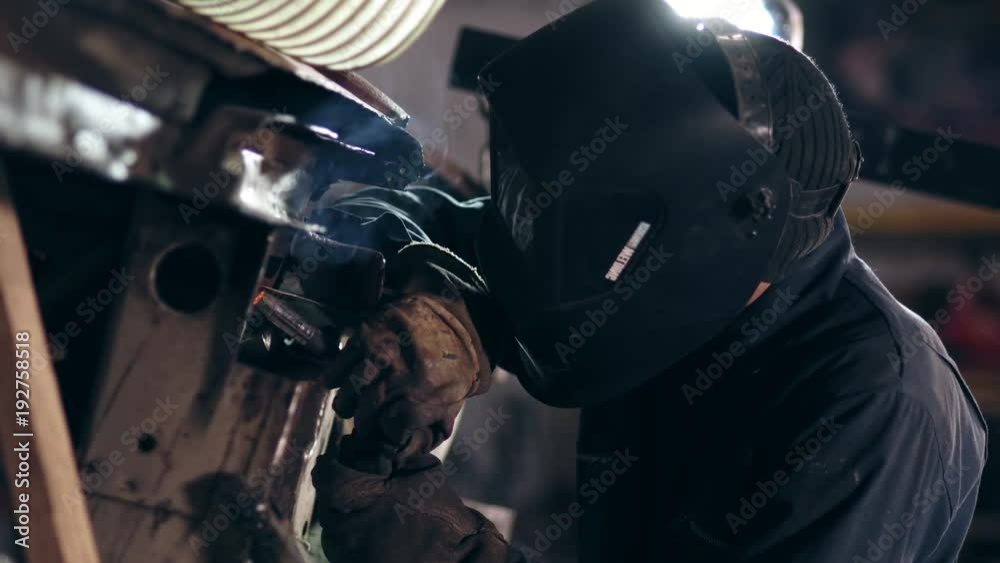 Male worker at a welding factory in a welding mask. Welding on an industrial plant. Slow motion. Male worker at a welding factory in a welding mask. Welding on an industrial plant. Slow motion.