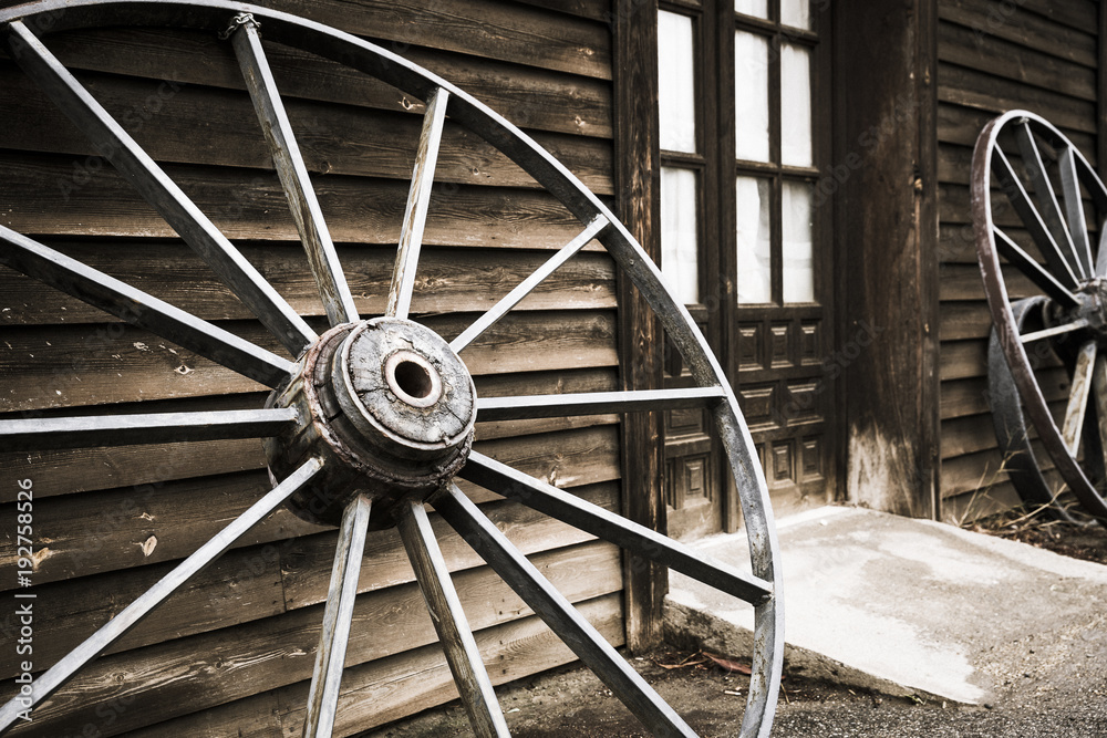 wheels of an old chariot leaning against the wall of a wooden made house