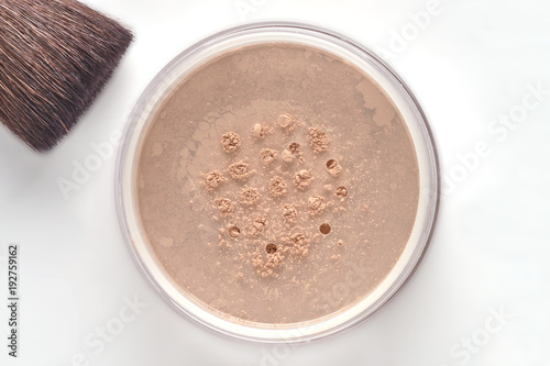 Cosmetic powder for face in jar and brush on white background.