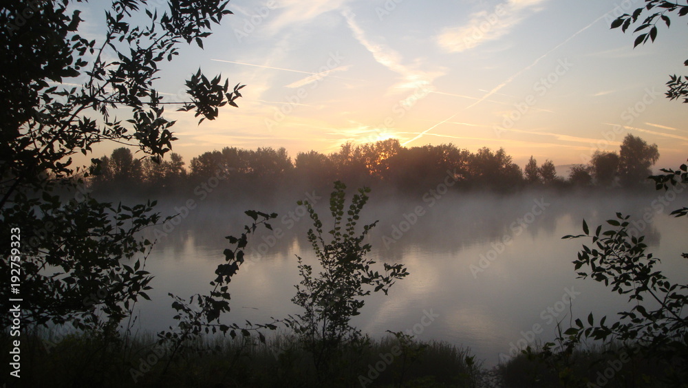 Fototapeta premium Morning fog on the river early in the morning. The sun was just rising. Fog on the water spreading. On the banks of the trees cast shadows on the water.