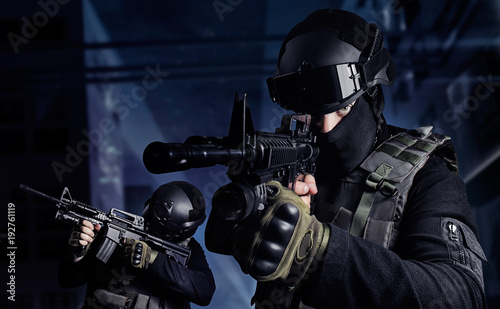 Photo of a swat soldiers posing with automatic rifles on a night city background.