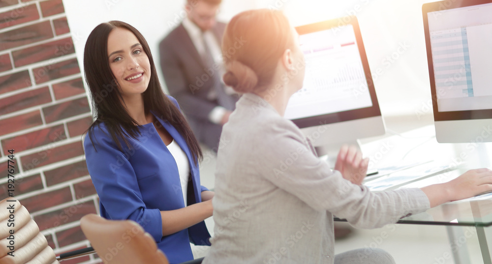 Two young business woman working together in office space