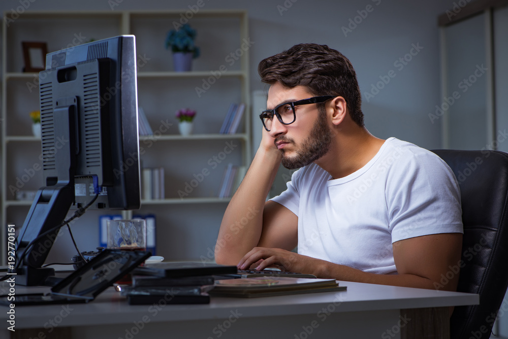 Young man staying late in office to do overtime work Young man staying late in office to do overtime work