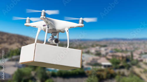 Unmanned Aircraft System (UAS) Quadcopter Drone Carrying Blank Package Over Neighborhood.