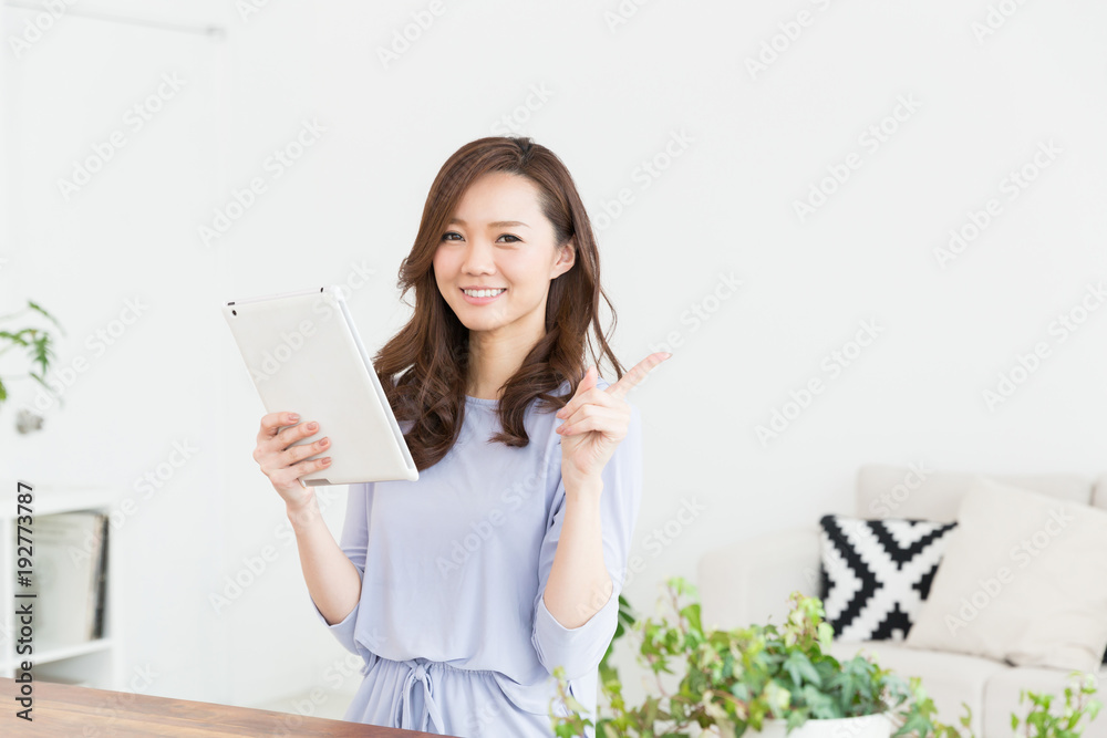 部屋でタブレットを見る女性 部屋でタブレットを見る女性