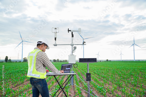 Engineer using tablet computer collect data with meteorological instrument to measure the wind speed, temperature and humidity and solar cell system on corn field background, Smart agriculture concept photo