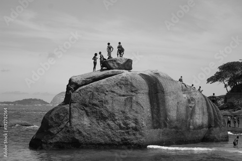 friends on top of a stone preparing the jump on Vidigal beach in the city of rio de janeiro black and white photo