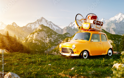 Cute little retro car with suitcases and bicycle on top on grass field at mou...