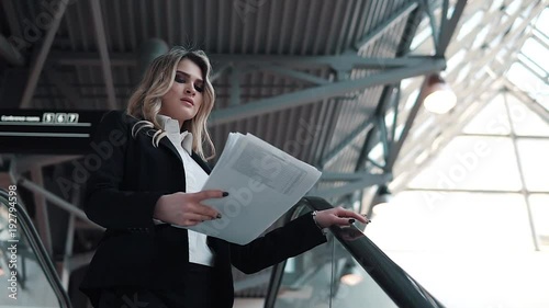 Wallpaper Mural a woman in a business suit descends on an escalator in a large office building. business woman holding documents Torontodigital.ca