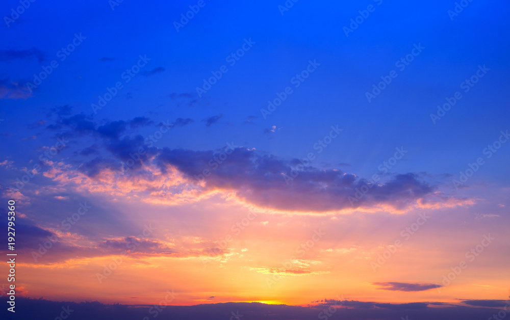 Beautiful colorful sunset sky background with the light of sun behind.Blue and purple clouds.