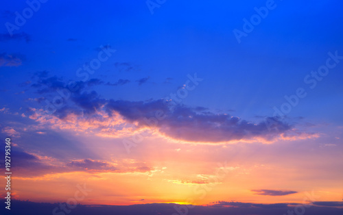 Beautiful colorful sunset sky background with the light of sun behind.Blue and purple clouds.