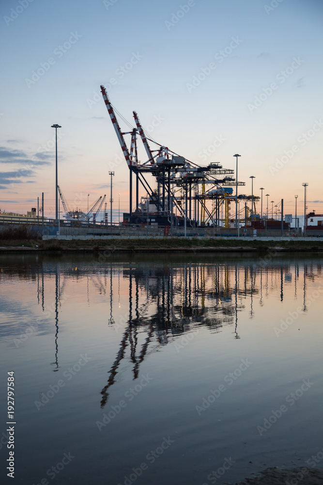 Container Terminal, Shipyard and Cranes at Sunset and Their Reflection Container Terminal, Shipyard and Cranes at Sunset and Their Reflection