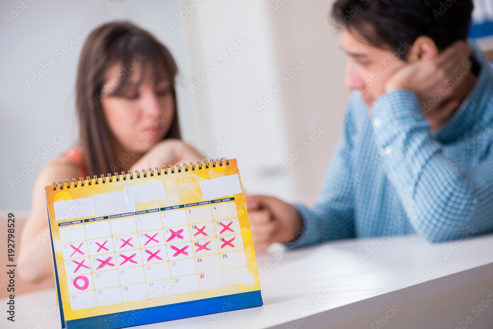 Young family in pregnancy planning concept with ovulation calendar Young family in pregnancy planning concept with ovulation calendar