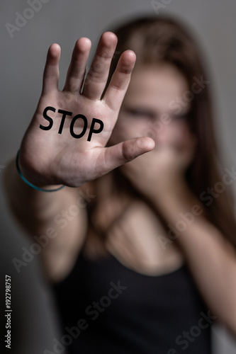 Teenage girl shows the inscription "stop" on the palm and closes her mouth with her hand
