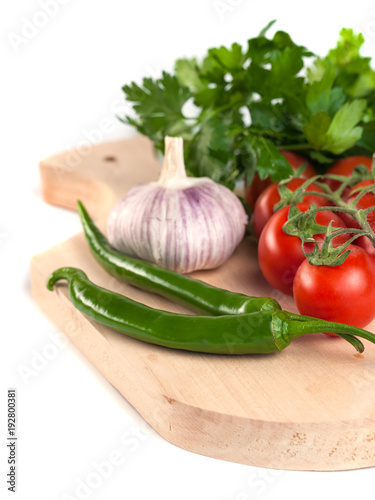tomatoes, parsley, garlic and green peppers on the wooden cutting board, white background