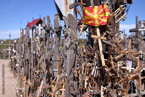 Krzyże drewniane, metalowe, żeliwne na Górze Krzyży, Litwa, pomiędzy krzyżami flaga Macedonii, słonecznie