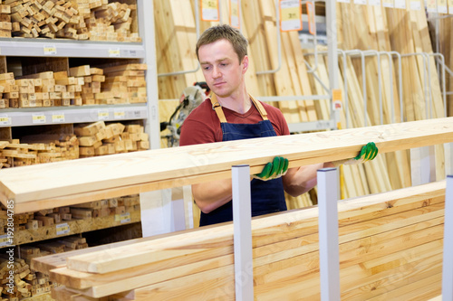фотографія worker or seller in construction store or warehouse wood department at work